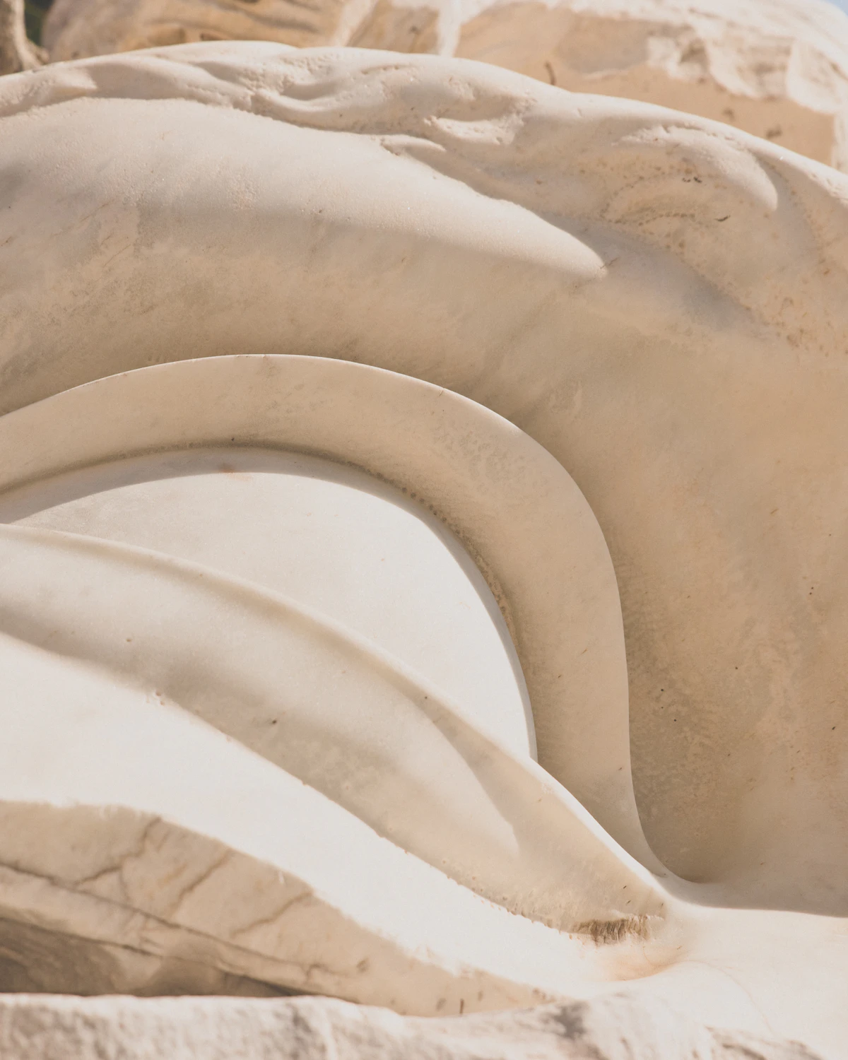 Marbre sculpté en lumière rasante, ombres longues — la matière comme langage